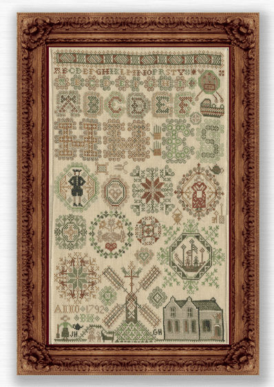A framed cross-stitch sampler featuring a windmill and a house.  